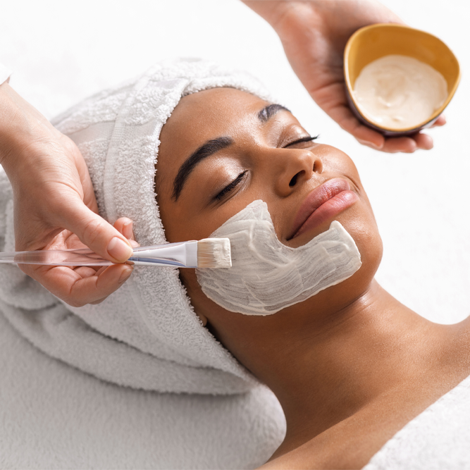 Top view of beauty therapist applying face mask on african woman skin, closeup